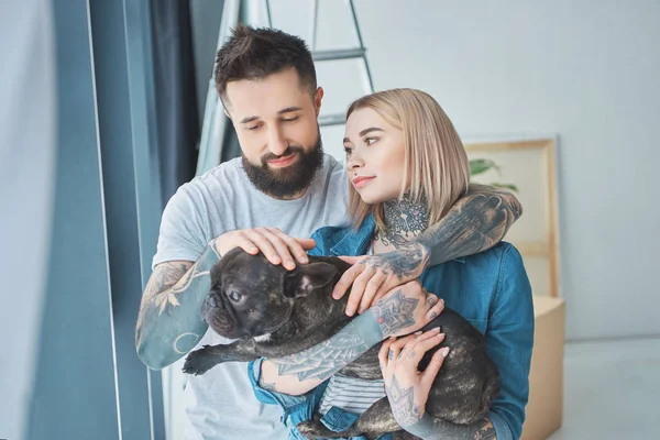 Retrato de casal tatuado com bulldog francês em nova casa — Fotografia de Stock