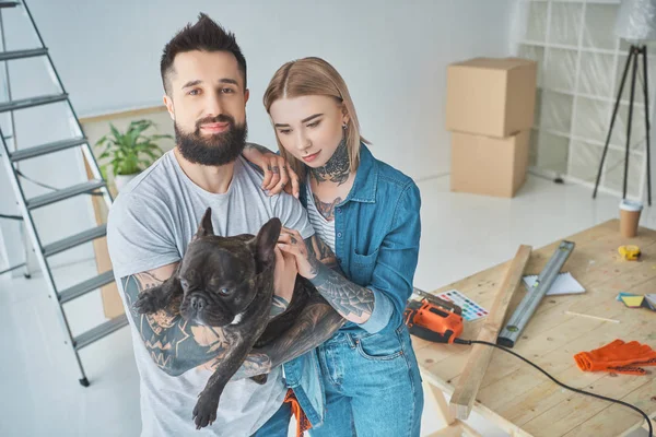 Casal tatuado com bulldog francês em nova casa — Fotografia de Stock