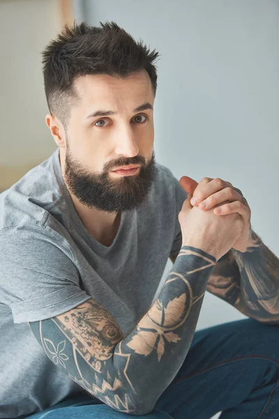 Retrato de hombre barbudo con tatuajes mirando a la cámara - foto de stock