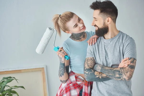 Porträt einer Frau mit Pinsel und Rolle, die ihren Freund im neuen Zuhause ansieht — Stockfoto