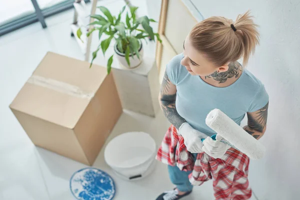 Tätowierte Frau mit Rollmalpinsel im neuen Zuhause — Stockfoto