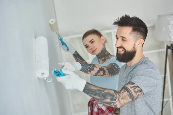 Side view of young couple painting wall together at new apartment — Stock Photo
