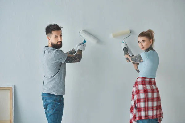 Vue arrière du mur de peinture de jeune couple ensemble au nouvel appartement — Photo de stock