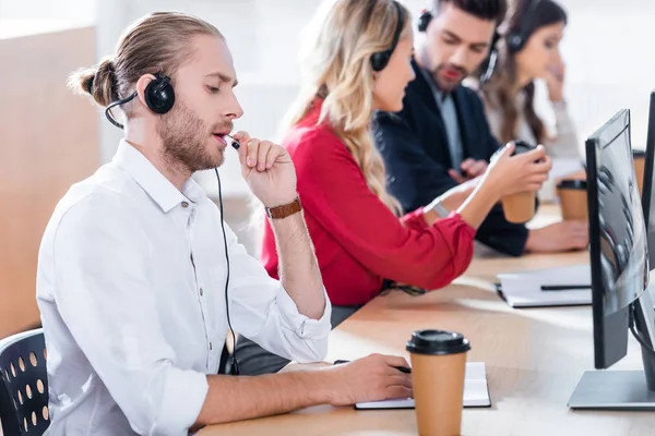 Selective focus of call center operators working at workplace with coffee to go in office — Stock Photo