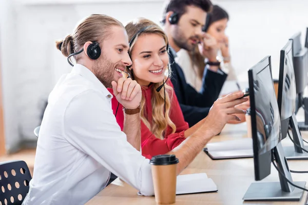 Foco seletivo de operadores de call center sorridentes trabalhando no local de trabalho com café para ir no escritório — Fotografia de Stock
