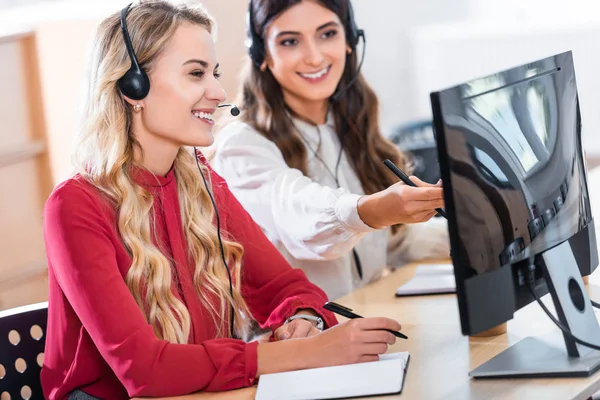 Opératrices de centre d'appels souriantes travaillant sur le lieu de travail au bureau — Photo de stock