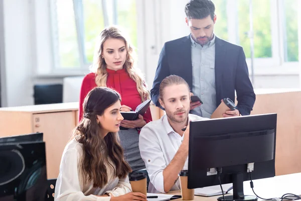 Giovani colleghi di lavoro che lavorano a un progetto aziendale insieme sul posto di lavoro con schermo del computer in ufficio — Foto stock