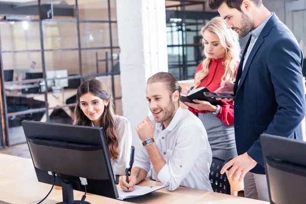 Jóvenes colegas de negocios que trabajan en el proyecto empresarial juntos en el lugar de trabajo con pantalla de ordenador en la oficina - foto de stock