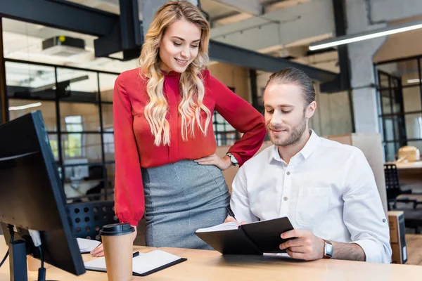 Businessman and businesswoman working on project together at workplace with computer screen in office — Stock Photo