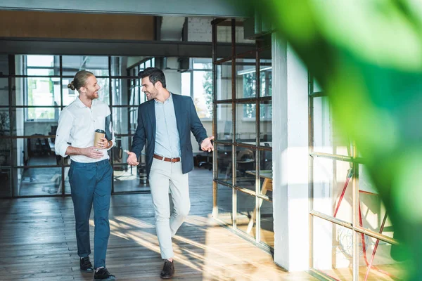 Smiling business colleagues having conversation while walking in hall — Stock Photo