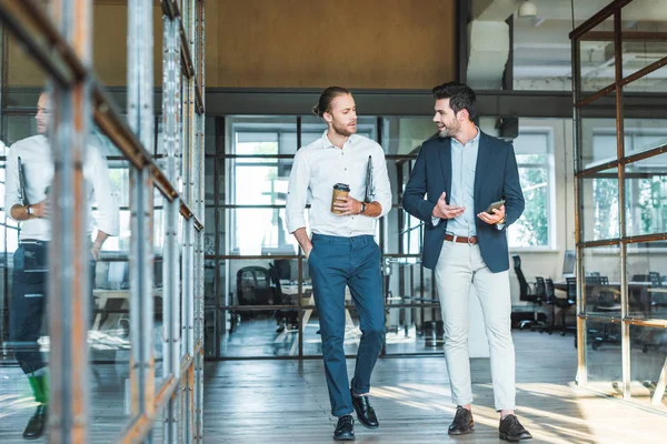 Smiling business colleagues having conversation while walking in hall — Stock Photo