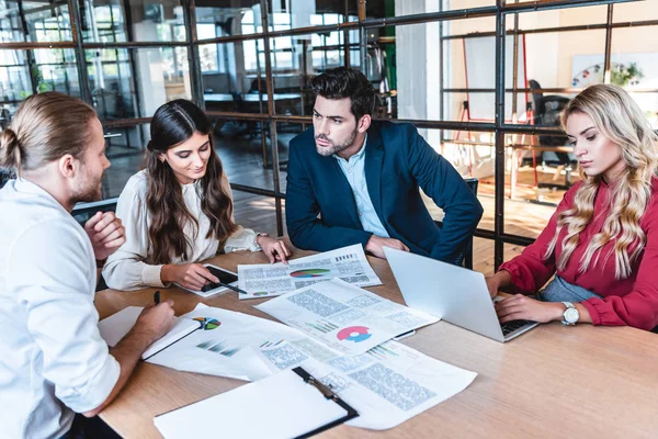 Business team discussing new business project at workplace with papers and laptop in office — Stock Photo