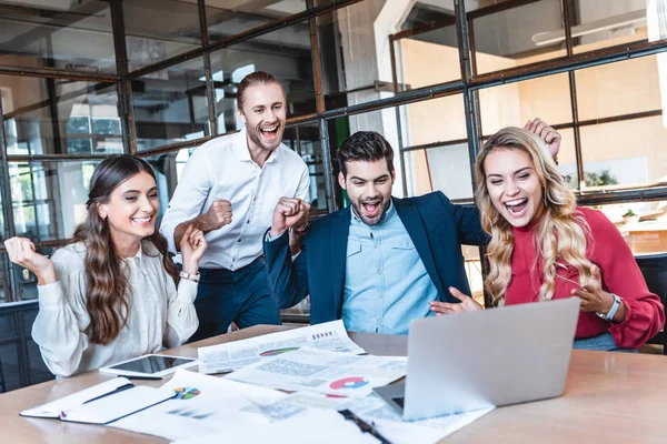 Happy successful business team looking at laptop screen at workplace in office — Stock Photo