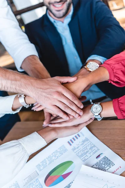 Cropped shot fo business team holding hands at workplace in office — Stock Photo