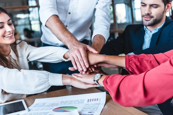 Cropped shot fo business team holding hands at workplace in office — Stock Photo