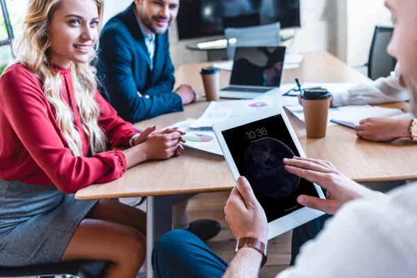 Vue partielle de l'homme d'affaires utilisant une tablette tout en étant assis à la table avec des collègues au bureau — Photo de stock