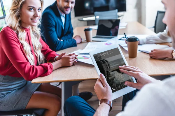 Abgeschnittene Aufnahme von Geschäftsmann mit digitalem Tablet bei der Online-Buchung von Tickets während der Arbeit mit Kollegen im Büro — Stockfoto