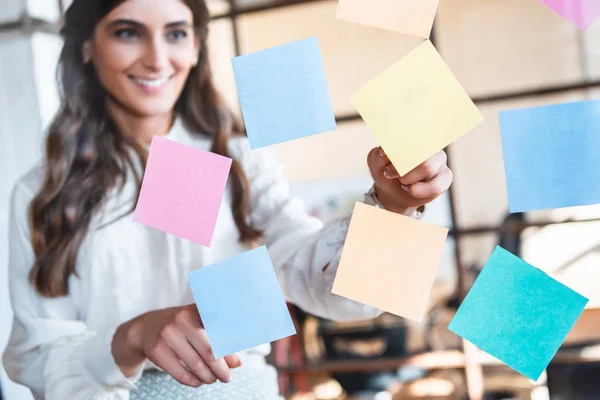 Souriant jeune femme d'affaires travaillant avec des notes collantes dans le bureau — Photo de stock