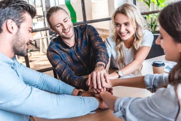 Happy young business team stacking hands at workplace — Stock Photo