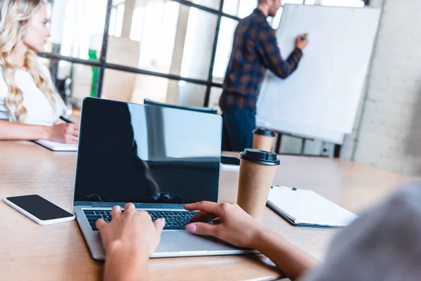 Recortado recortado de la persona de negocios utilizando el ordenador portátil con pantalla en blanco durante la reunión con los colegas - foto de stock