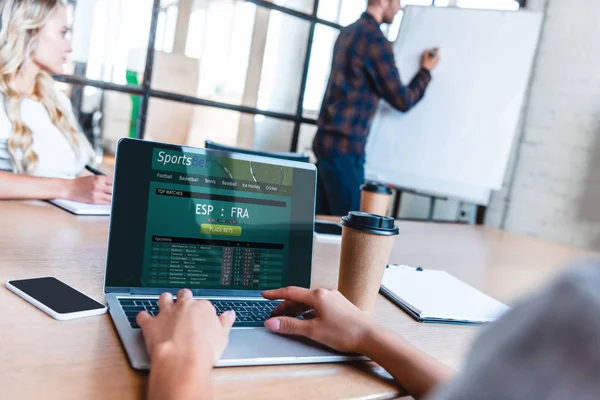 Abgeschnittene Aufnahme eines Geschäftsmannes mit Laptop und Sportwetten-App auf dem Bildschirm während eines Treffens mit Kollegen — Stockfoto