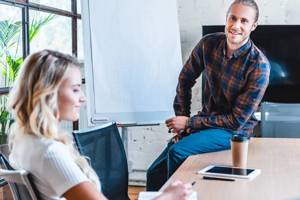 Sonriendo jóvenes colegas de negocios trabajando juntos en la oficina - foto de stock