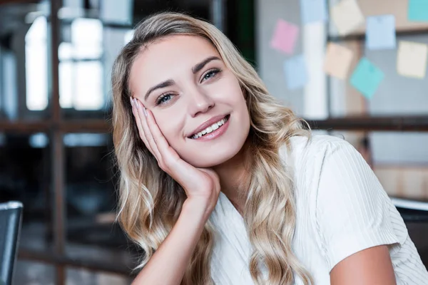 Porträt der schönen jungen blonden Geschäftsfrau, die im Büro in die Kamera lächelt — Stockfoto