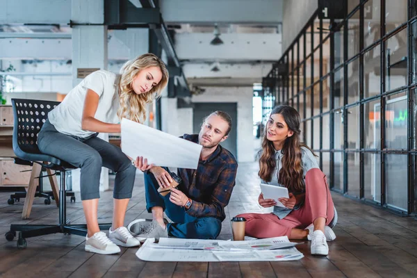 Young coworkers sitting together and working with business charts in office — Stock Photo