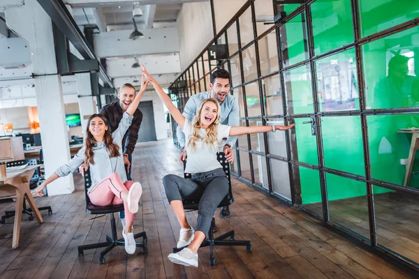 Jóvenes empresarios felices divirtiéndose juntos en el espacio de trabajo - foto de stock