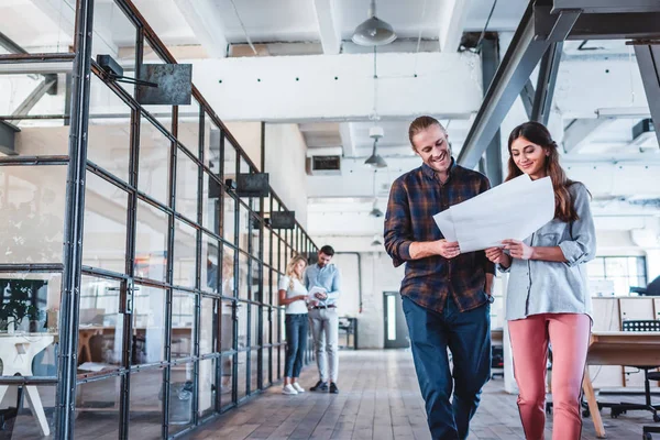 Lächelnde junge Geschäftskollegen, die am Arbeitsplatz mit Dokumenten arbeiten — Stockfoto