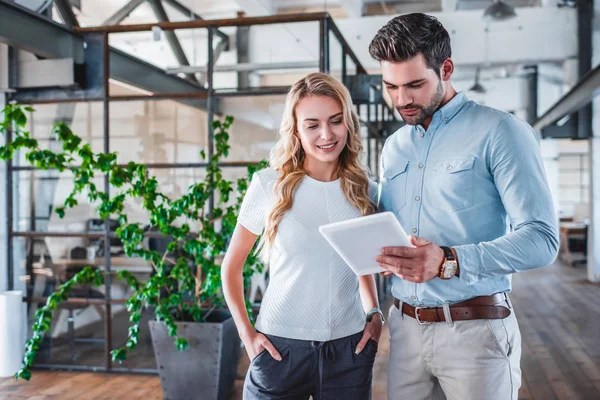 Lächelnde junge Mitarbeiter mit digitalem Tablet am Arbeitsplatz — Stockfoto