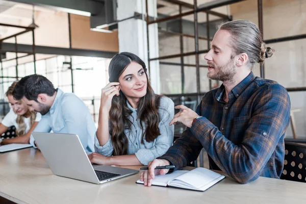 Young smiling business colleagues talking and working together in office — Stock Photo