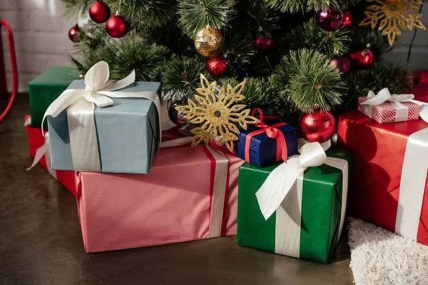 Bunte Geschenke unter dem Weihnachtsbaum mit Kugeln im Zimmer — Stockfoto