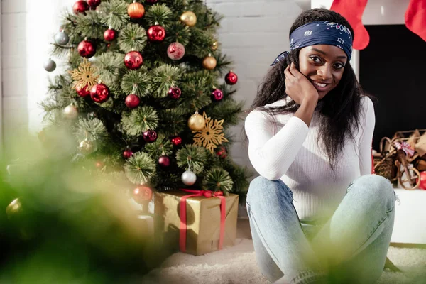 Lächelnd schöne afrikanisch-amerikanische Frau, die zu Hause in die Kamera schaut, Weihnachtskonzept — Stockfoto