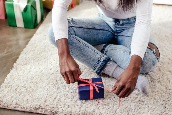 Cropped image of african american woman opening christmas gift at home — Stock Photo