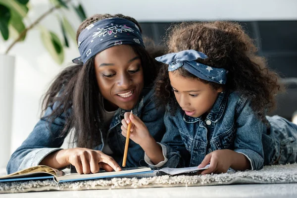 Portrait of african american woman helping daughter doing homework at home — Stock Photo