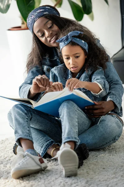 African american mother and daughter looking at family photo album at home — Stock Photo