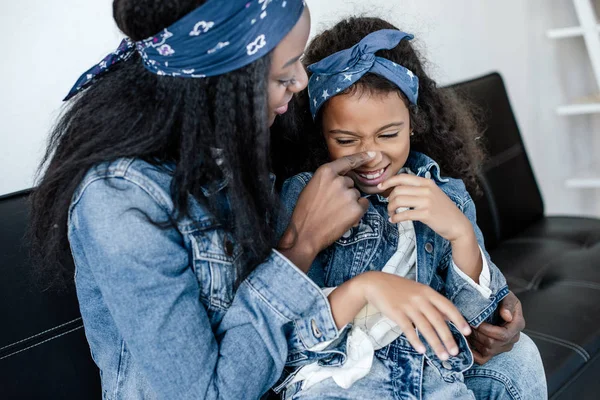 Donna afroamericana e figlia allegra divertirsi sul divano di casa — Foto stock