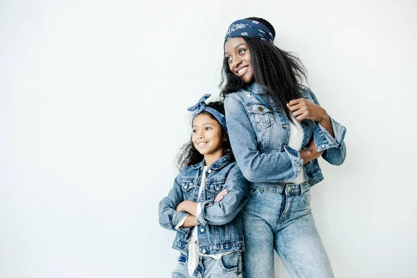 Elegante afro-americano mãe e filha em roupas semelhantes posando na parede em casa — Fotografia de Stock