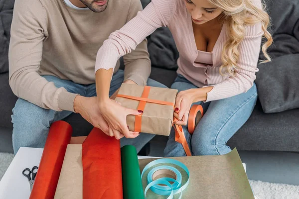 Imagem cortada de casal embrulhando caixa de presente de Natal juntos em casa — Fotografia de Stock