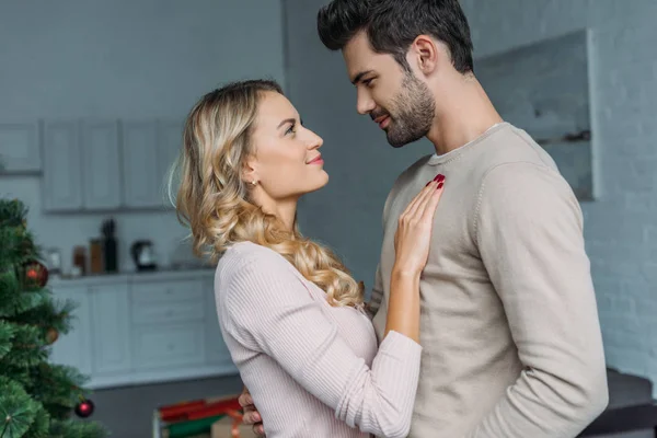 Carinhoso casal abraçando na cozinha e olhando uns para os outros — Fotografia de Stock