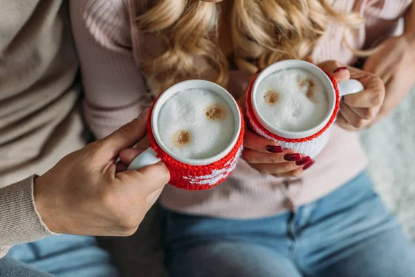 Cropped image of couple clinking with cups of cappuccino at home, christmas concept — Stock Photo