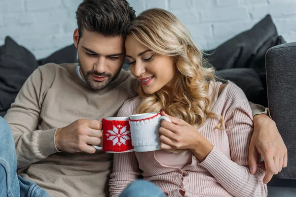 Couple clinking with cups of cappuccino at home, christmas concept — Stock Photo