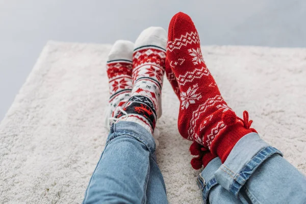Corte imagem casal sentado no tapete em jeans e meias de Natal — Fotografia de Stock