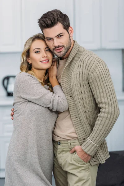 Couple joyeux étreignant et regardant la caméra dans la cuisine — Photo de stock