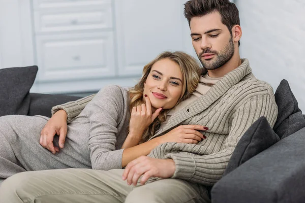 Affectionate heterosexual couple lying on sofa in living room — Stock Photo