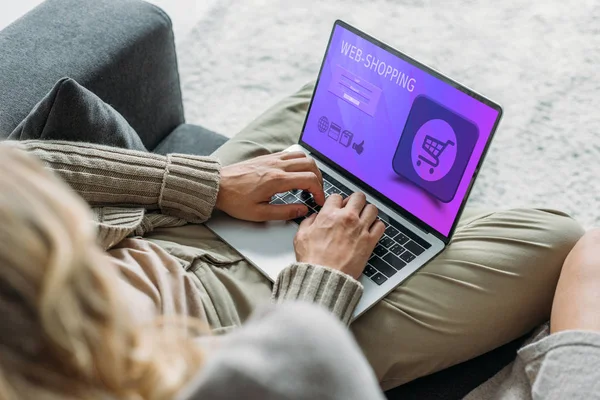 Cropped shot of couple using laptop with web-shopping website on screen on couch at home — Stock Photo