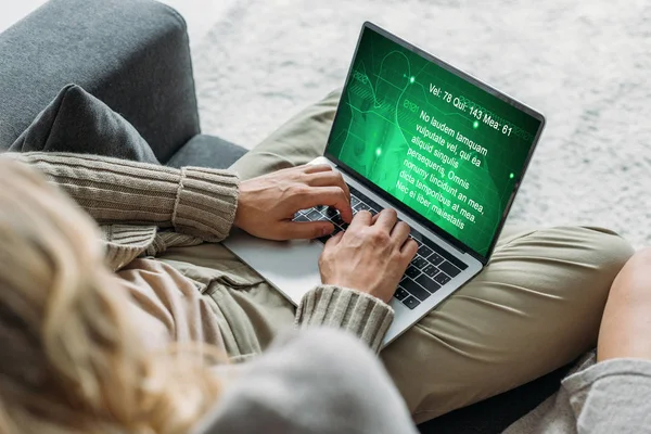 Cropped shot of couple using laptop with with business graphs on screen on couch at home — Stock Photo