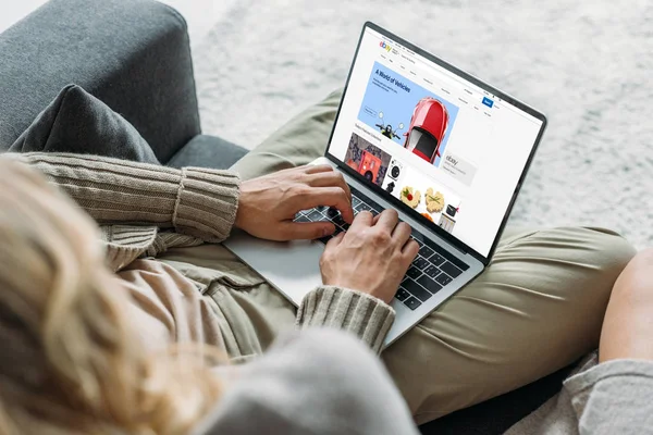 Abgeschnittene Aufnahme eines Paares mit Laptop und ebay-Website auf dem Bildschirm auf der heimischen Couch — Stockfoto