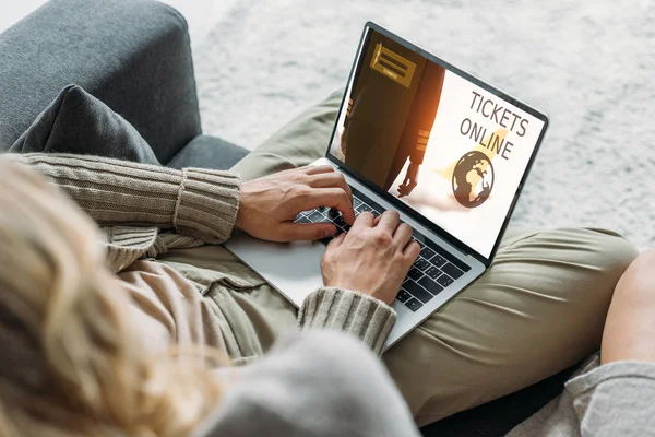 Abgeschnittene Aufnahme eines Paares mit Laptop und Ticketbuchungswebseite auf dem Bildschirm auf der heimischen Couch — Stockfoto